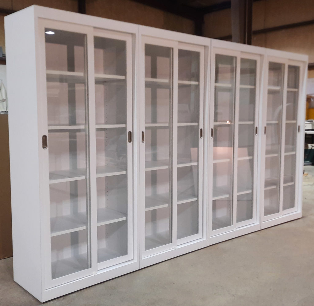 Tall white bookcase with glass doors and integrated LED puck lighting