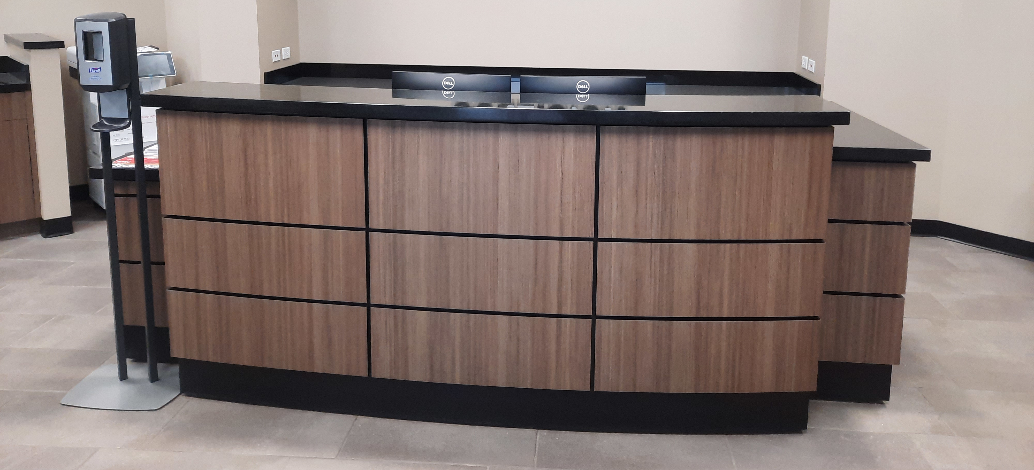 Custom reception desk with wood grain laminate face and black quartz work surfaces
